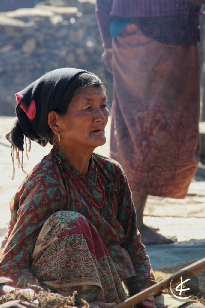Frau sitzt auf dem Boden und klopft Getreide