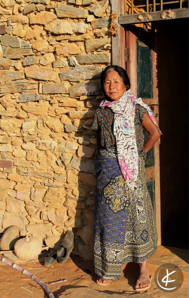 Frau steht angelehnt an einem Steinhaus