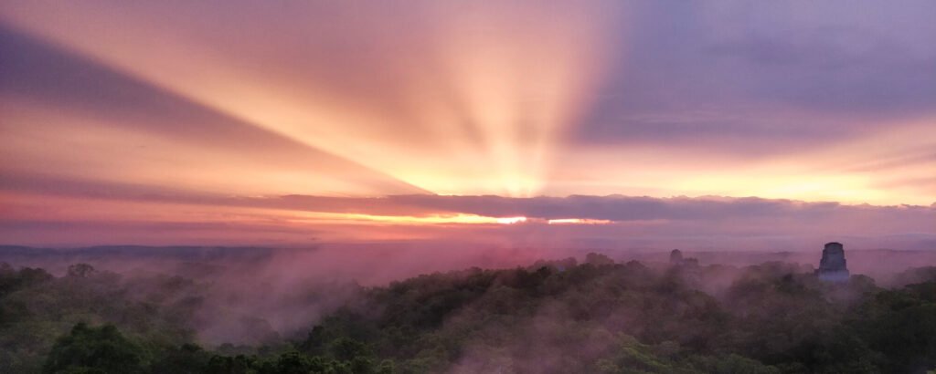 Sonnenaufgang über den Berggipfeln von Tikal
